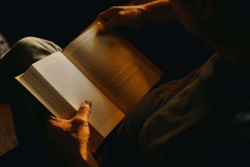 Man Reading a Book Indoor at Dusk